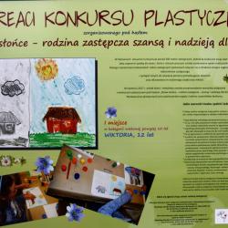 Prace laureatów konkursu plastycznego pod hasłem Nowe słońce - rodzina zastępcza szansą i nadzieją dla dzieci - 1 miejsce w kategorii powyżej 10 lat. Praca przedstawia szary dom po lewej i kolorowy po prawej stronie.