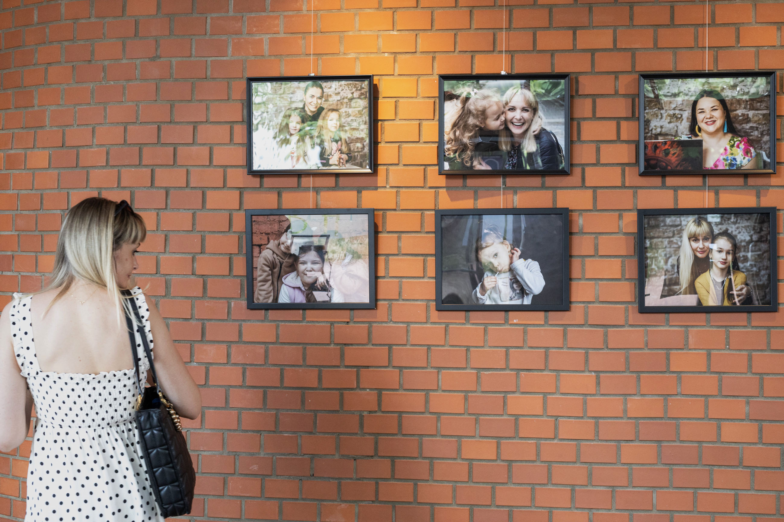 Zdjęcie przedstawia kobietę stojącą i oglądającą zdjęcia zaprezentowane podczas wystawy.